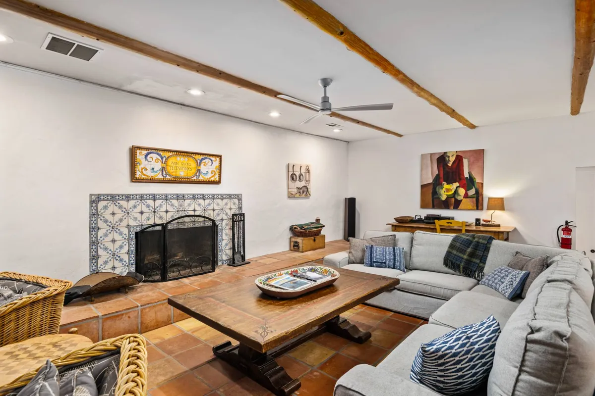 A cozy living area with a plush sofa and coffee table arranged around a warm fireplace, complemented by inviting artwork on the walls. The open layout suggests space for both relaxation and togetherness, with a view that hints at easy indoor-outdoor flow ideal for families and their pets.